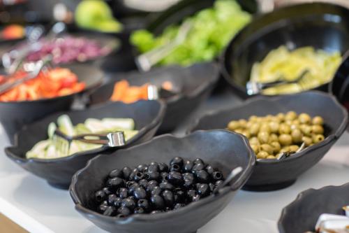 a table topped with black bowls filled with different types of food at Batumi View Luxury in Batumi