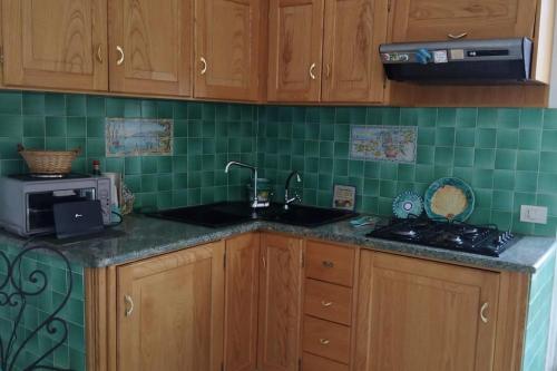 una cocina con armarios de madera y azulejos verdes en My Way, en Positano