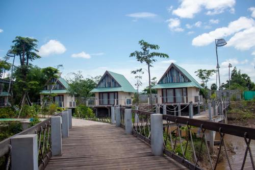 a wooden walkway leading to a resort with houses at Kampot Eco Village in Kampot