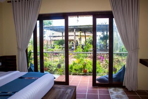 a bedroom with a view of a garden through a glass door at Kampot Eco Village in Kampot