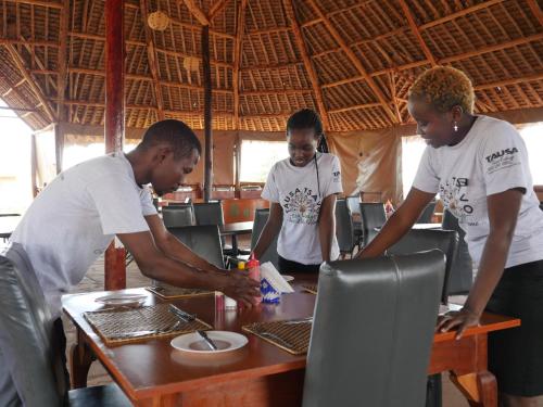 a group of people standing around a table with a laptop at Tausa Tsavo Eco Lodge in Voi