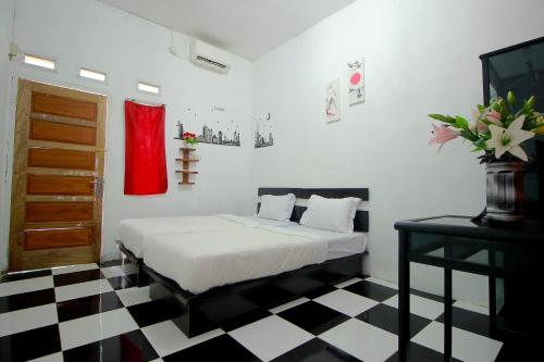 um quarto com uma cama e um piso em xadrez preto e branco em OYO 2362 Wisma Ria em Lubuklinggau