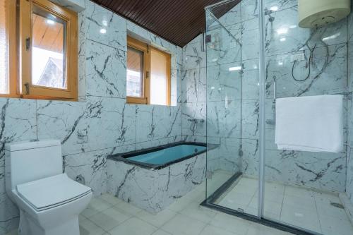 a bathroom with a glass shower and a toilet at StayVista at Pinewood Villa with Pool Table in Srinagar