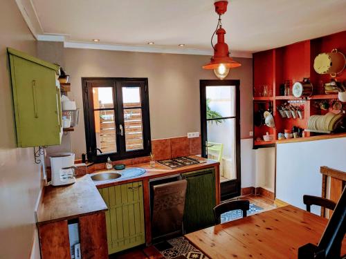 une cuisine avec des placards rouges et verts et une table dans l'établissement Maison 3 niveaux avec terrasse, 2 chambres, animaux acceptés – centre Le Palais - FR-1-418-136, au Palais