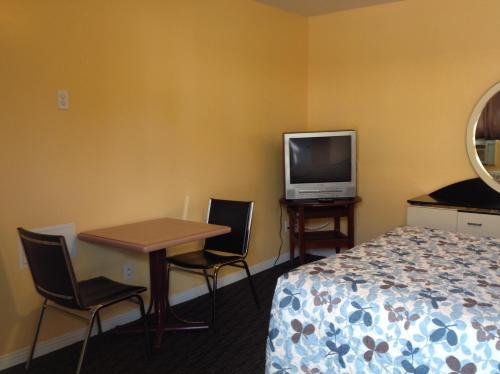 Habitación de hotel con cama, mesa y TV. en Motel Saint-Jacques, en Montreal