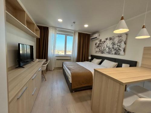 um quarto com uma cama, uma televisão e uma secretária em Apart Astana em Taldykolʼ