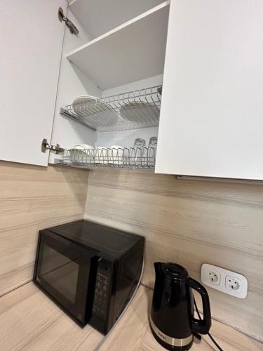 a microwave sitting on a kitchen floor next to a cupboard at Apart Astana in Taldykolʼ