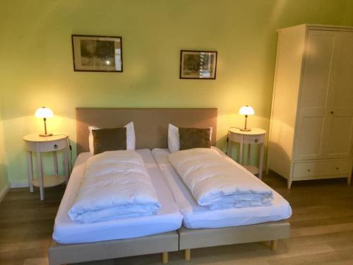 a large bed in a room with two side tables at HEINRICHs winery bed & breakfast in Langenlonsheim