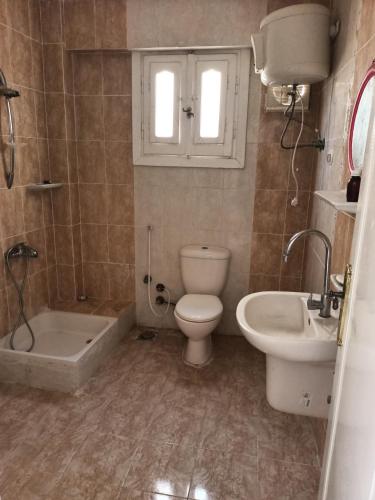 a bathroom with a toilet and a tub and a sink at شاليه في قرية هيلو بيتش في الكيلو ٥٠ in Borg El Arab