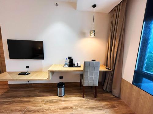 a room with a desk with a tv and a chair at Sachika Hotels, Guwahati in Guwahati