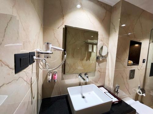 a bathroom with a white sink and a mirror at Sachika Hotels, Guwahati in Guwahati