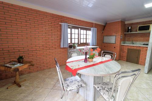 Habitación con mesa, sillas y pared de ladrillo. en Loft bem equipado com WiFi em Bento Goncalves RS, en Bento Gonçalves