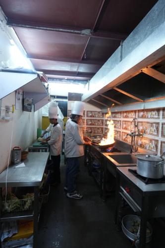two chefs standing in a kitchen preparing food at Hotel Square One by D'Polo Dharamshala in Dharamshala