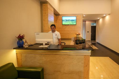 a man standing at a counter with a computer at Hotel Square One by D'Polo Dharamshala in Dharamshala