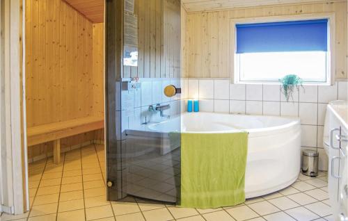 a bathroom with a large tub and a window at Gorgeous Home In Hvide Sande With Sauna in Havrvig