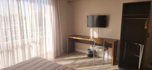 a bedroom with a desk with a television on it at DAKAR HOTEL in Mendoza