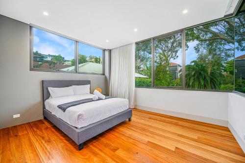 Un dormitorio con una cama y grandes ventanales. en Putney Brand New Luxury House Pool & Waterview, en Sídney