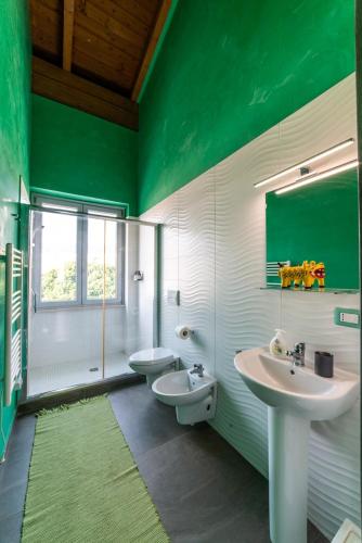 a green and white bathroom with two sinks and a toilet at Speciale Tarshito's Home - Atrium and Terrace in Bari