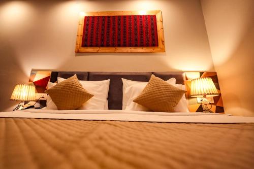 a bedroom with a bed with pillows and two lamps at Hotel Square One by D'Polo Dharamshala in Dharamshala
