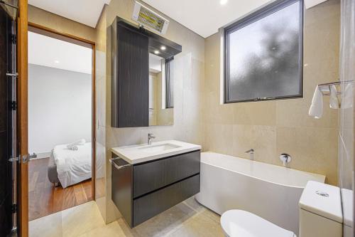 Un baño con bañera, lavabo e inodoro. en Putney Brand New Luxury House Pool & Waterview, en Sídney