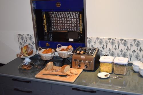 Una encimera de cocina con pan, una tostadora y otros alimentos. en Domaine du Kaegy - Hébergements 5 étoiles, en Steinbrunn-le-Bas