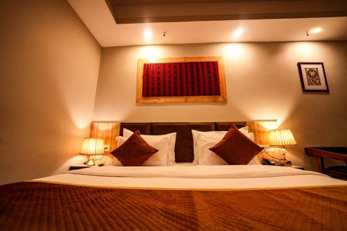 a bedroom with a large bed with two lamps at Hotel Square One by D'Polo Dharamshala in Dharamshala