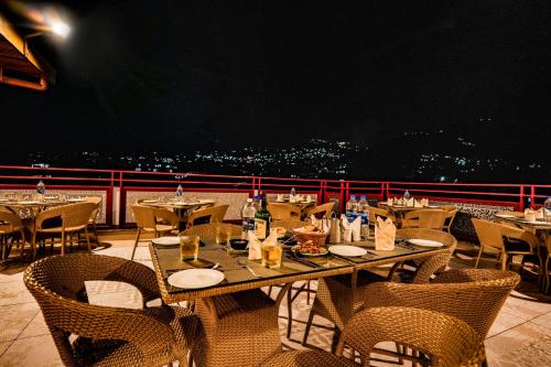 a restaurant with tables and chairs on a balcony at Hotel Square One by D'Polo Dharamshala in Dharamshala