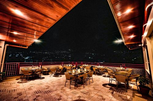 a restaurant with tables and chairs on a balcony at Hotel Square One by D'Polo Dharamshala in Dharamshala