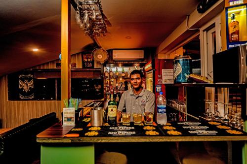 a man standing behind a bar in a pub at Hotel Square One by D'Polo Dharamshala in Dharamshala