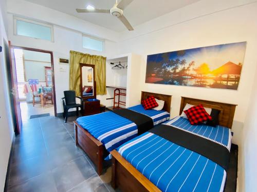 a bedroom with two beds and a living room at Hotel 100 in Dehiwala