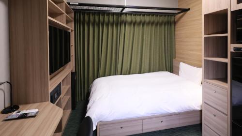 Dormitorio pequeño con cama y TV en Dormy Inn Aomori Natural Hot Spring, en Aomori