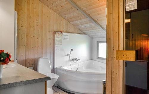 BjerregårdにあるNice Home In Hvide Sande With Wifiのバスルーム(白いバスタブ、トイレ付)