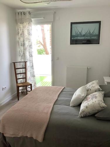 une chambre avec un lit avec une chaise et une fenêtre dans l'établissement Carnac grand appartement cosy 2 personnes, à Carnac