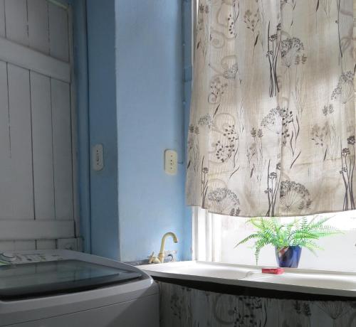 a bathroom with a window and a curtain with a plant at AXÉ HOME Martha & Jorge in Salvador