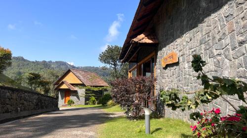 a building with a stone wall next to a road at The Wild Trails Clarks Exotica , Munnar in Munnar