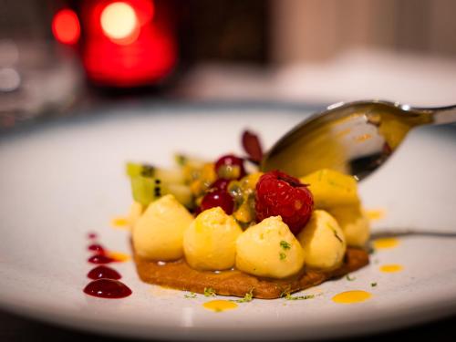 a plate of food with a spoon and fruit on it at Château de Candie in Chambéry