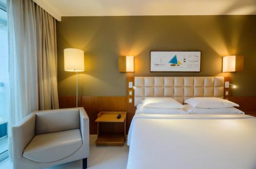 a hotel room with a bed and a chair at Hotel Luzeiros São Luis in São Luís