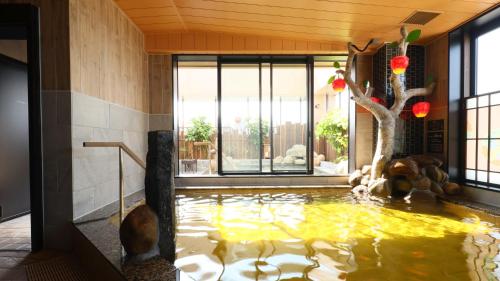 um lago de carpas numa sala com uma árvore em Dormy Inn Aomori Natural Hot Spring em Aomori