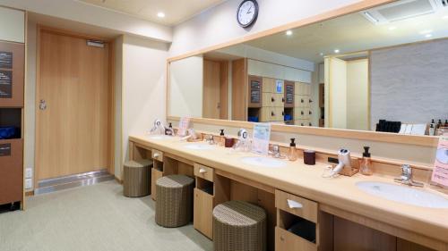 Dormy Inn Aomori Natural Hot Spring في أوموري: حمام به ثلاث مغاسل ومرآة كبيرة
