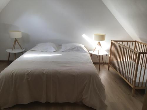 a bedroom with a white bed with two lamps and a crib at Ferme de la Haute-Escalles in Escalles