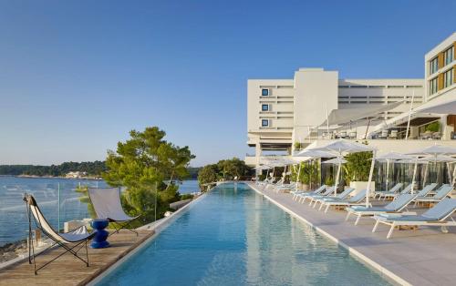 een zwembad met ligstoelen en een gebouw bij Grand Hotel Brioni Pula, A Radisson Collection Hotel in Pula