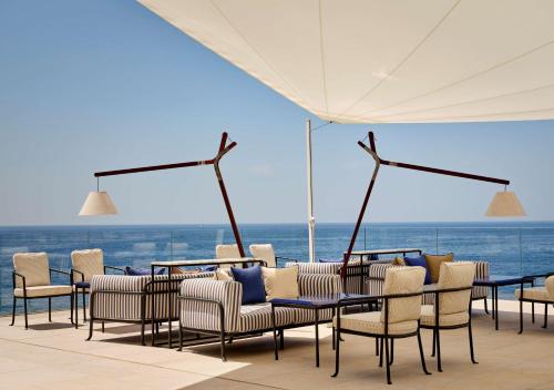 een groep stoelen en tafels met uitzicht op de oceaan bij Grand Hotel Brioni Pula, A Radisson Collection Hotel in Pula
