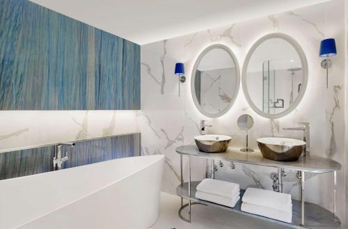 a bathroom with two sinks and two mirrors at Grand Hotel Brioni Pula, A Radisson Collection Hotel in Pula