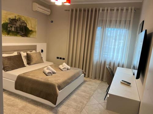 - une chambre avec un lit, un bureau et une télévision dans l'établissement Manga Apartments 3+1, à Gjirokastër