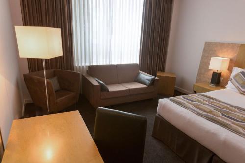 a hotel room with a bed and a couch and a chair at Park Plaza Cardiff in Cardiff