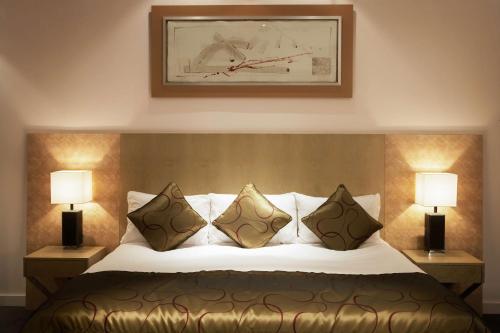 a bedroom with a bed with pillows and two lamps at Park Plaza Cardiff in Cardiff