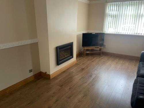 - un salon vide avec une cheminée et une télévision à écran plat dans l'établissement Contractors Accommodation, à Glyncorrwg