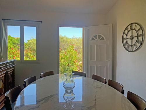 a dining room with a table with chairs and a clock at Résidence Maora Village in Bonifacio