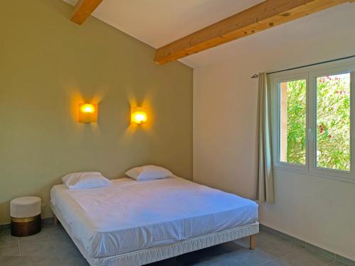 a bedroom with a bed and two lights on the wall at Résidence Maora Village in Bonifacio