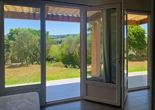 an open glass door with a view of a yard at Résidence Maora Village in Bonifacio